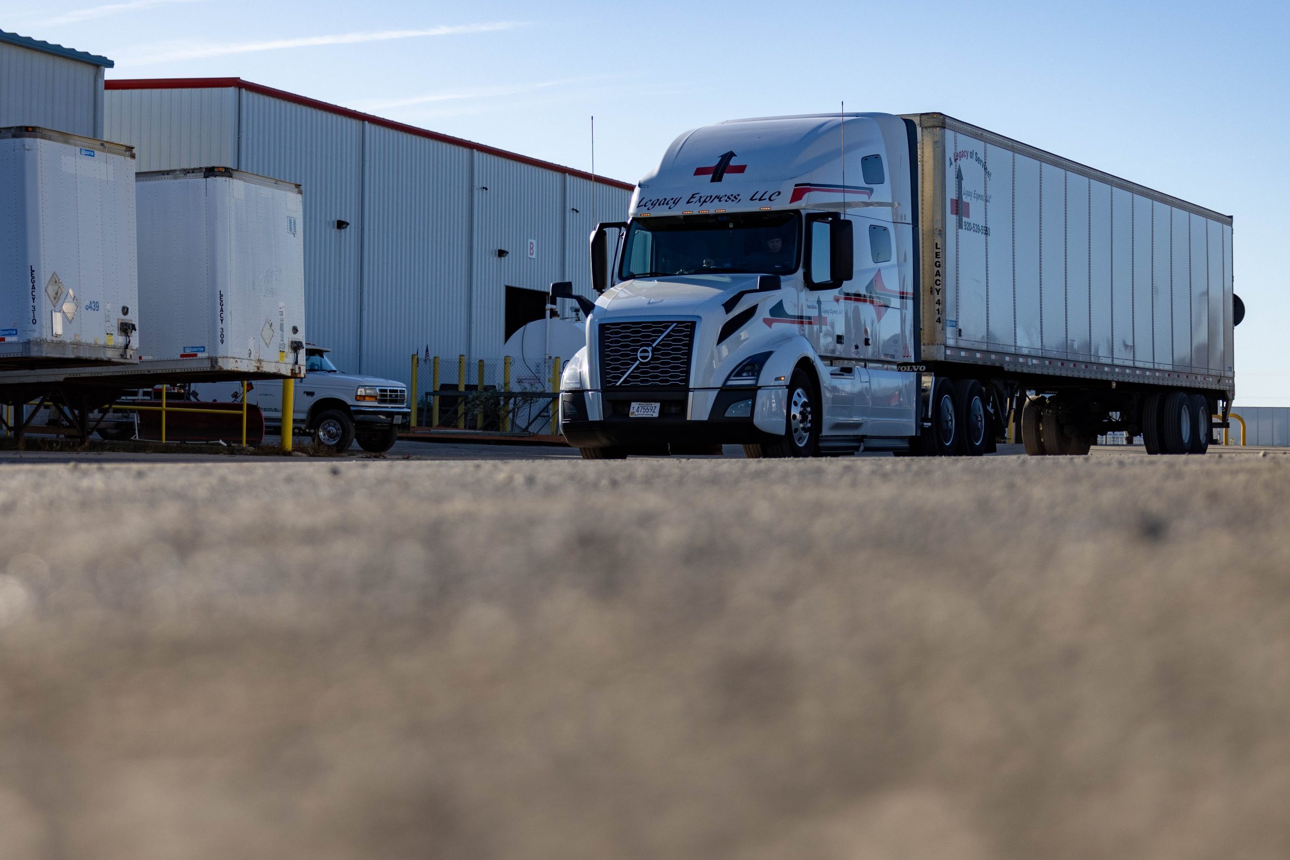 A branded, white Volvo truck parked outside a facility