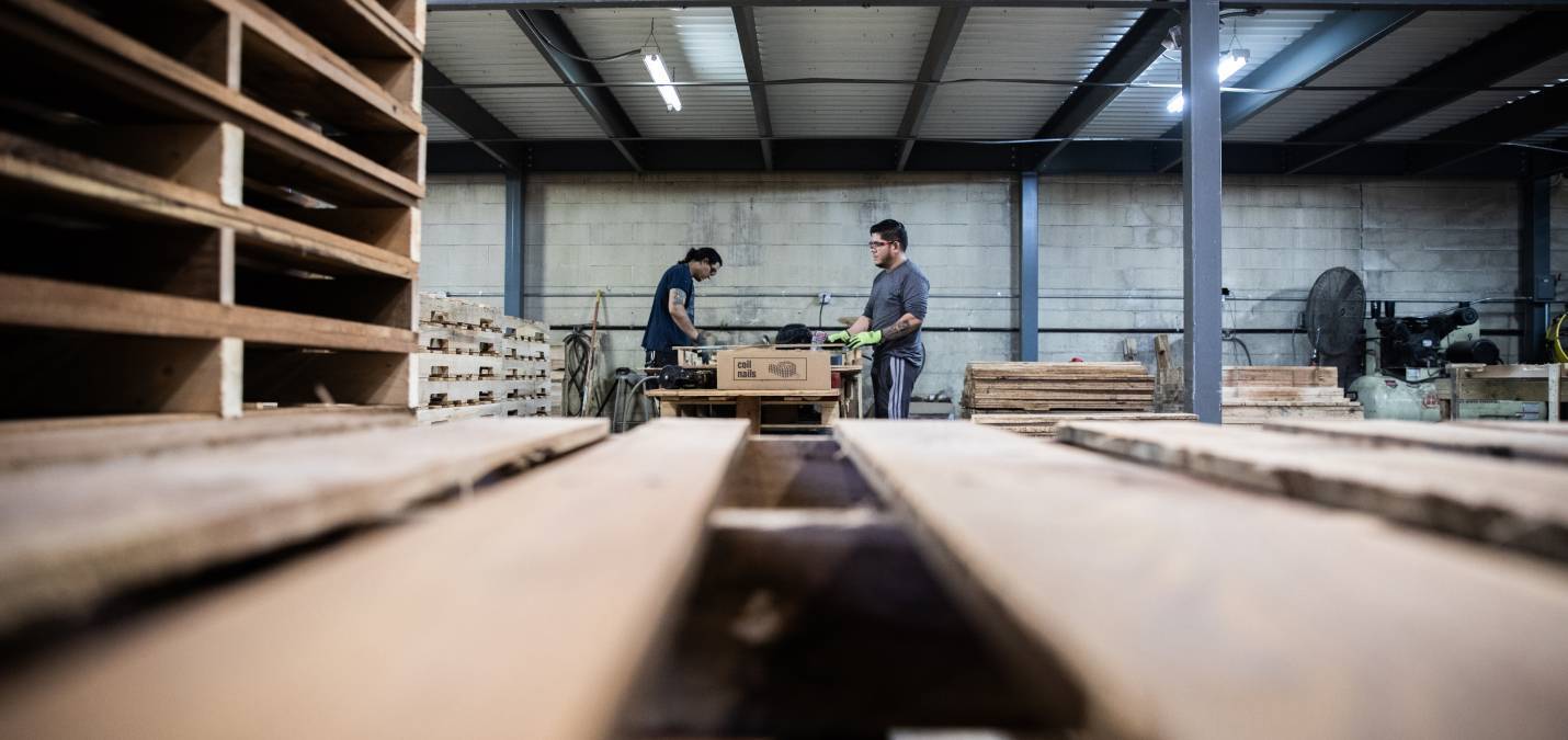 Two Logical & Packaging Logistics employees sealing boxes inside a warehouse