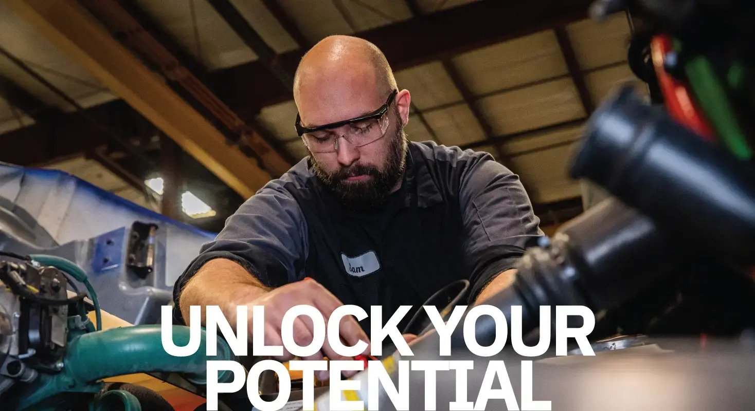 Kriete technician in a dark gray uniform and safety goggles, working on an engine