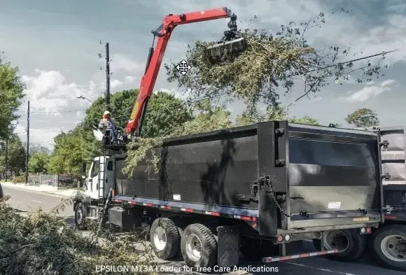 A red Palfinger epsilon loaders loading tree branches into a truck