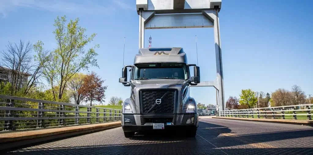 Dark grey Volvo truck driving across a bridge
