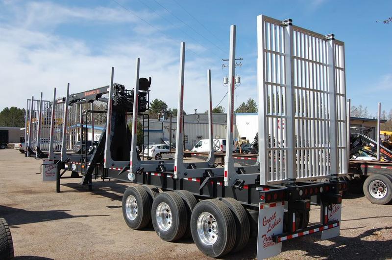 A Great Lakes log trailer seen from the side amidst other trailers
