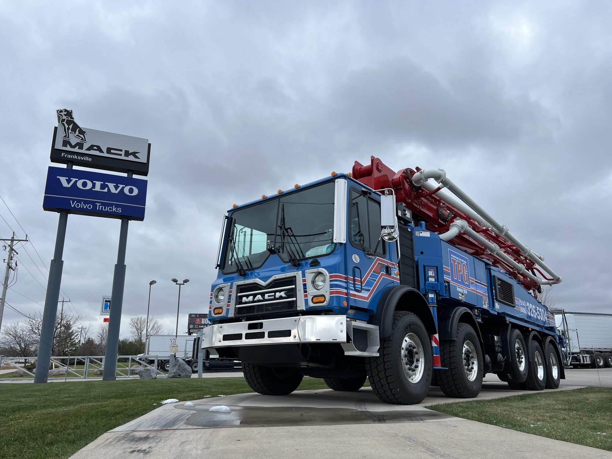 A blue and red Mack truck, beneath a cloudy sky