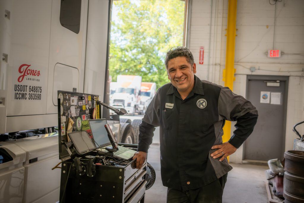 Kriete technician smiling at the camera while he performs diagnostic checks on a Jones Logistics-branded truck