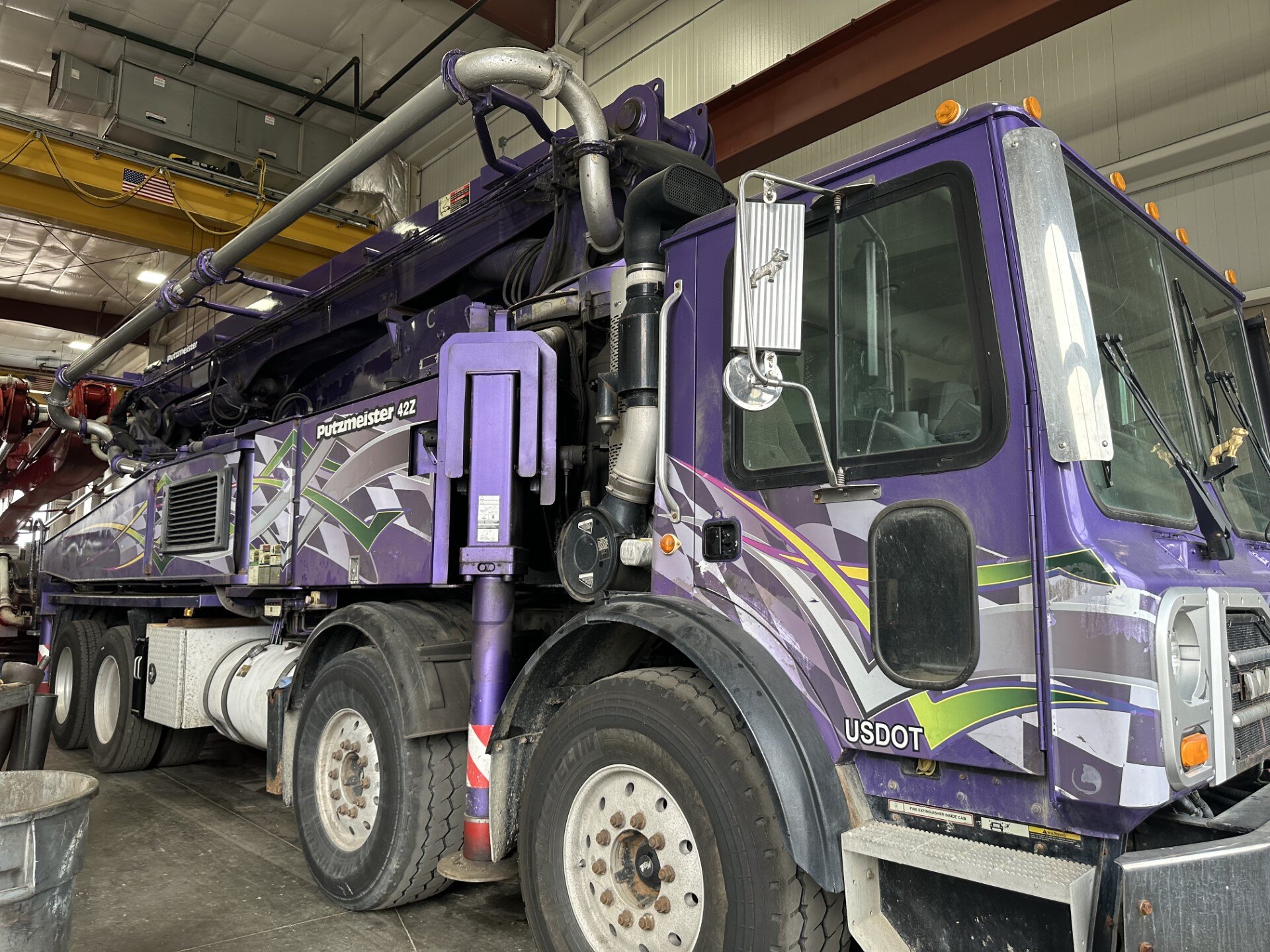 Purple Mack truck with a mounted Putzmeister pump