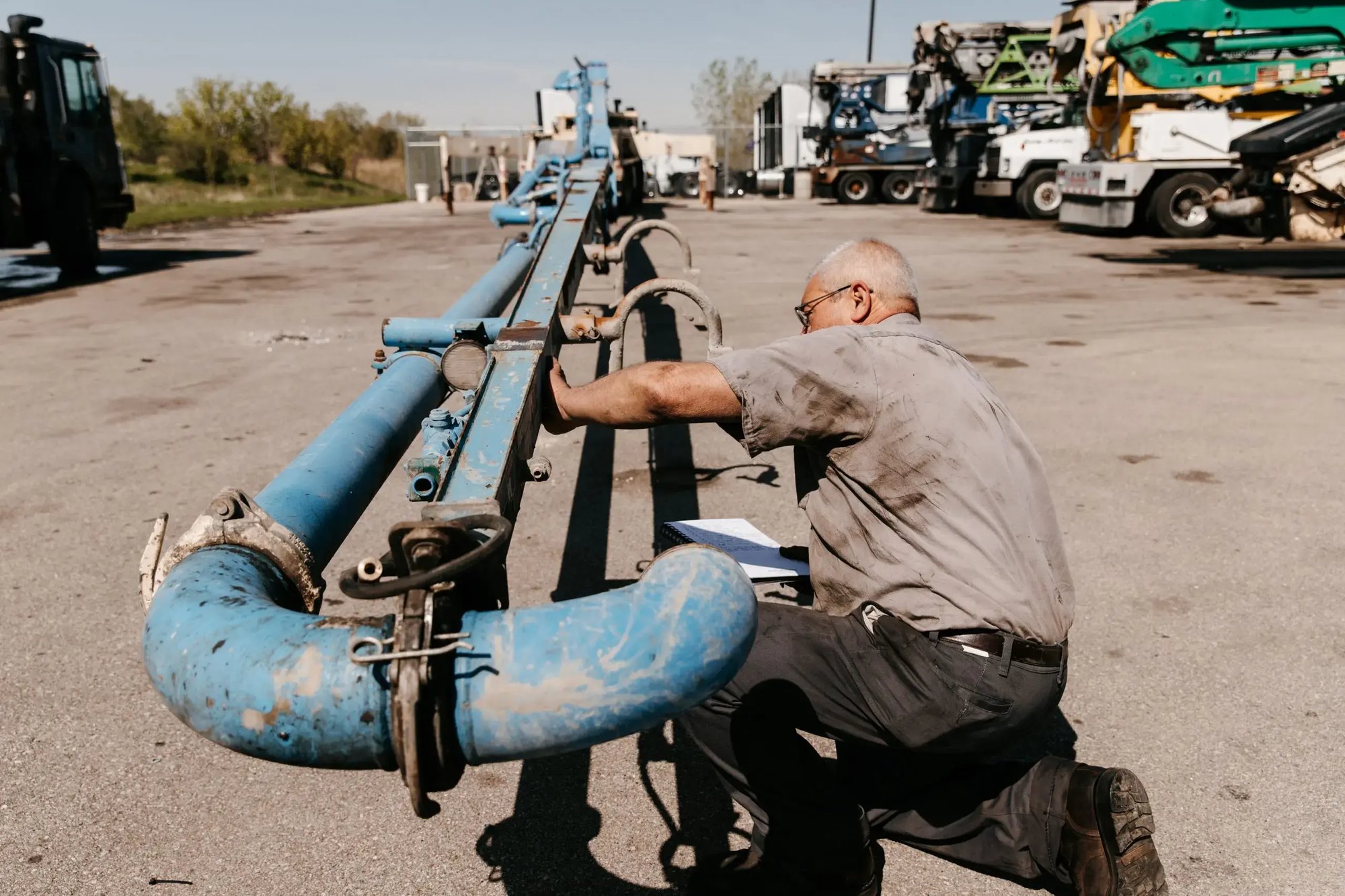 Mark Kelemen kneeling on the ground while inspecting a boom