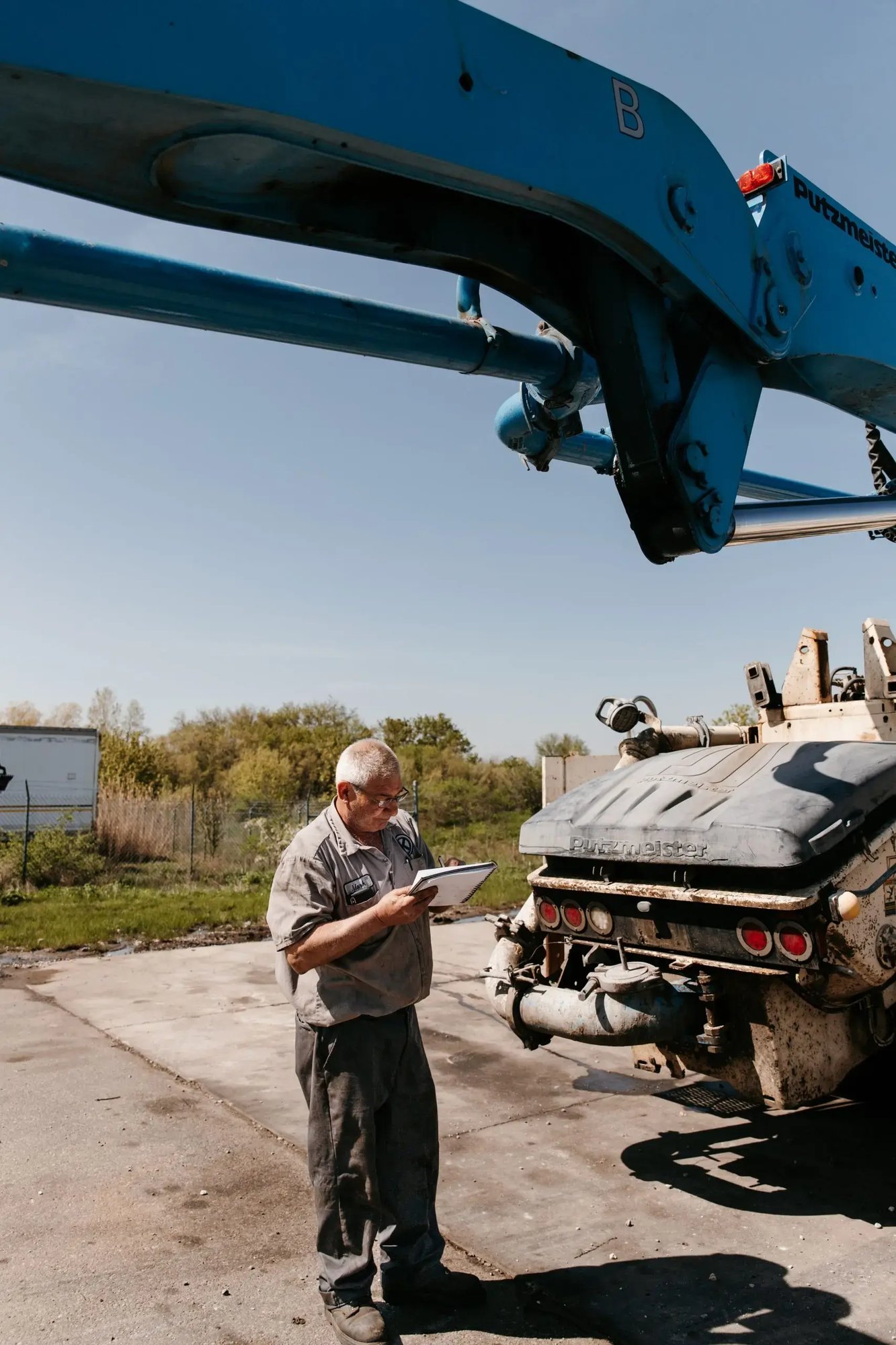 Mark Kelemen writing on a paper pad next to a truck with a projecting boom