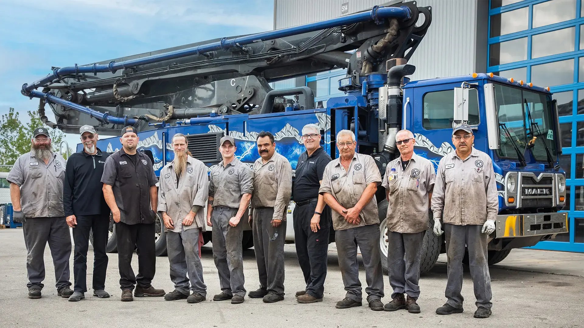 Members of the Putzmeister team standing in front of a large blue Mack truck