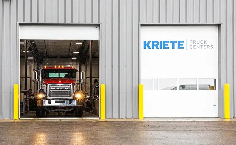 A large red Mack truck in the doorway of a warehouse