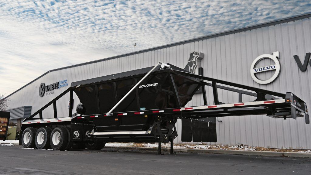 A black Cross Country belly dump trailer