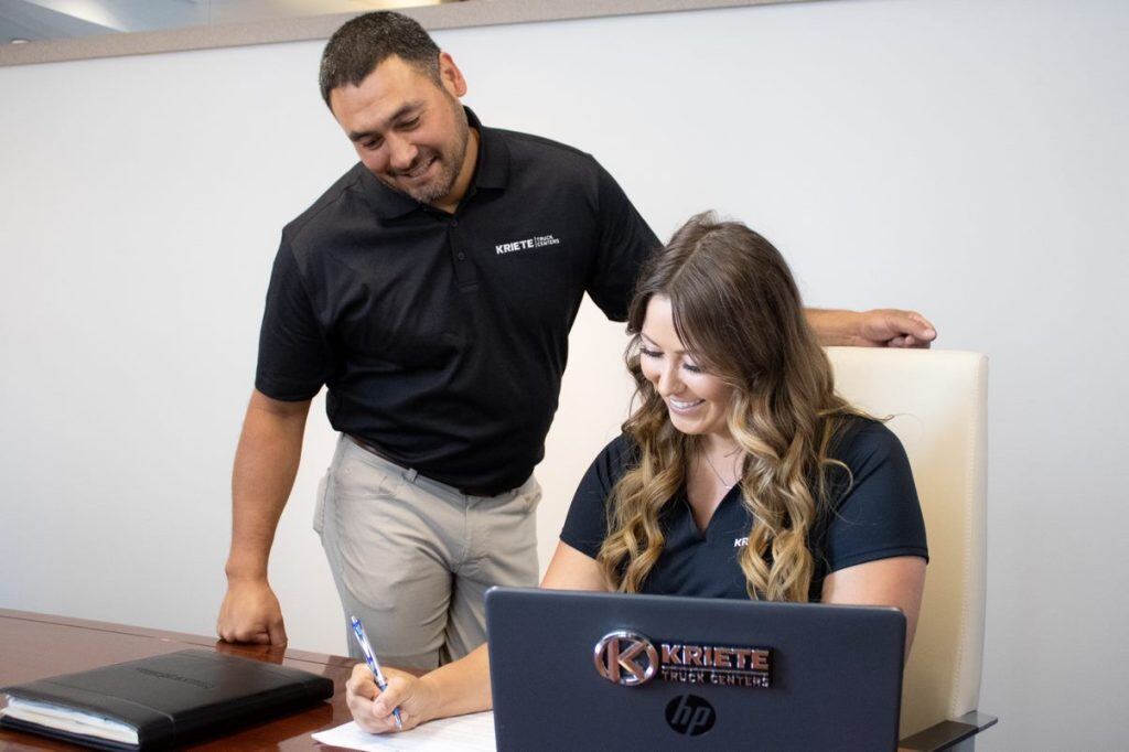 Two members of the Kriete finance and insurance team signing paperwork at a desk