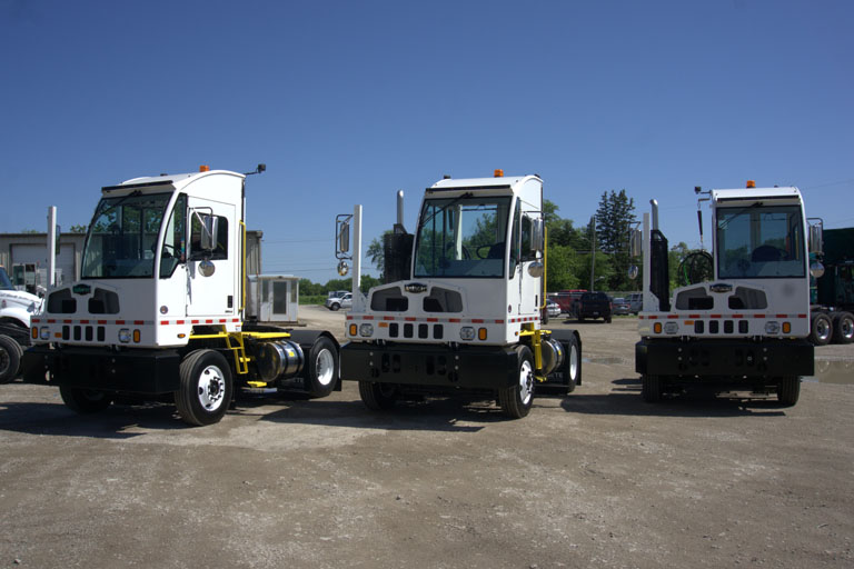 A trio of autocar trucks in a parking lot