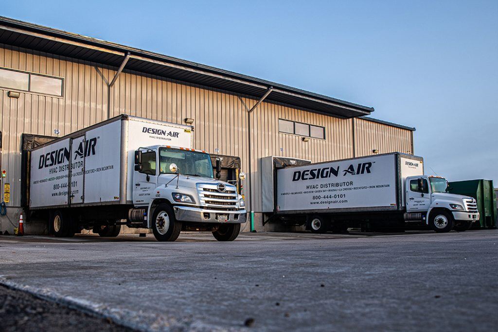 A pair of Hino L6 trucks parked outside a warehouse