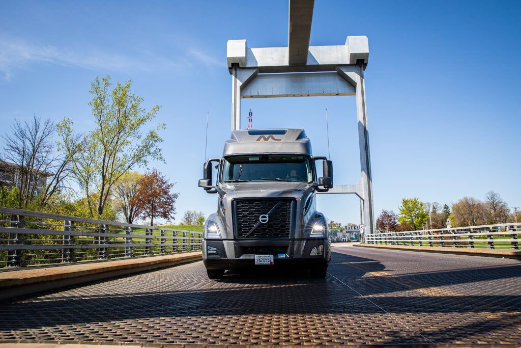A dark gray Volvo truck driving across a bridge